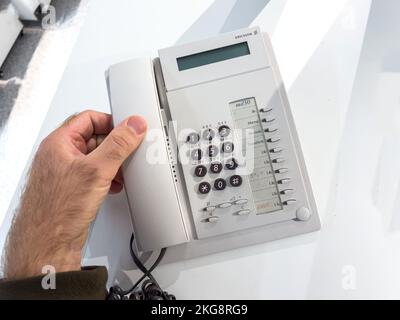Sweden - Oct 1, 2022: POV male hand holding hand on the Ericsson MD30 vintage wired phone on office table Stock Photo