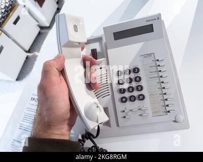 Sweden - Oct 1, 2022: POV male hand answering to a call - hand on the Ericsson MD30 vintage wired phone on office table Stock Photo
