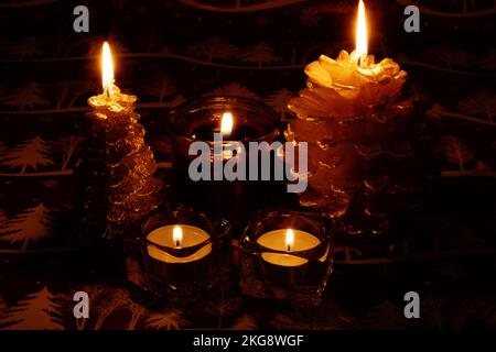 photo of lit candles of different shapes on the table Stock Photo