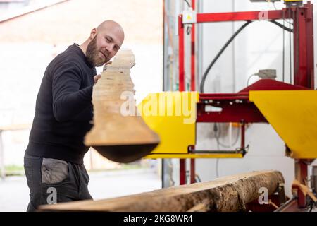 Young man working on the machine for processing the wood, huge wood cutter or saw, industrial concept Stock Photo
