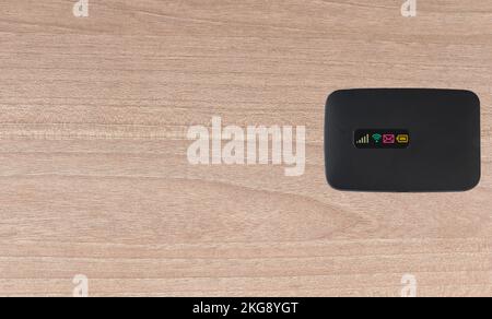 Portable pocket wifi modem on wooden background. black wifi  portable pocket modem top view. Stock Photo