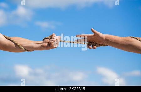 Rope, cord. Hand holding a rope, climbing rope, strength and determination. Rescue, help, helping gesture or hands. Conflict tug of war Stock Photo