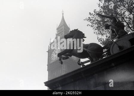 1950s, historical, a view of the Roman statue, 'Boadicea and Her Daughters' located in Westminster, seen against the Clock Tower (Big Ben) by the Palace of Westminter, home of the UK Goverment.  Representing Boudica, queen of the Celtic Iceni tribe who led an uprising in Roman Britain, the sculptor was Englisih artist and engineer, Thomas Thornycroft. Although completed in 1885, it was not until 1902 that it was cast in bronze and installed on the north side of Parliament Hill. Stock Photo