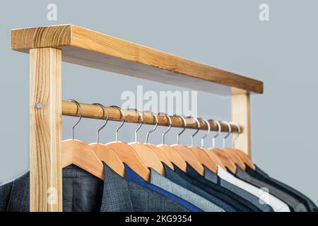 Mens shirts, suit hanging on rack. Hangers with jackets on them in boutique. Suits for men hanging on the rack. Mens suits in different colors hanging Stock Photo