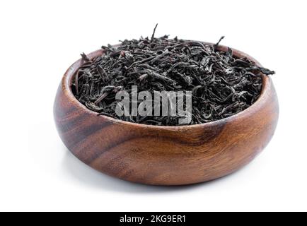 Black  tea leaves in wooden bowl isolated on white background Stock Photo