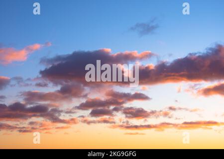 Contrasting cumulus clouds with a pink halo shape around, on gradient weather after sunset. Stock Photo