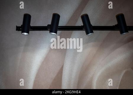 black modern lamps in the shape of a cylinder illuminate the wall Stock Photo
