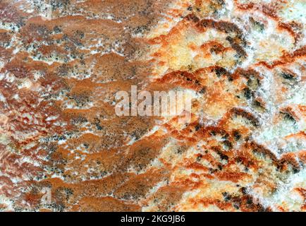 Quartz stone with brown, orange and white patterns. Background and texture of natural quartzite. Stock Photo