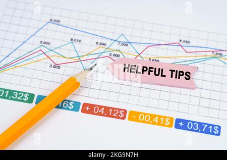 Business concept. On business charts there is a pencil and an arrow sticker with the inscription - Helpful Tips Stock Photo