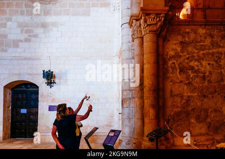 Visitors viewing the Annunciation capital. Monastery of San Juan de Ortega is a Romanesque monument in Barrios de Colina, Montes de Oca, Burgos, Casti Stock Photo