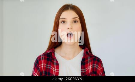 Surprised ginger girl student teenager feel good shock admiration female face excited winner says wow positive reaction holds head by hands successful Stock Photo