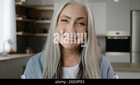 Positive elderly retiree woman look at web camera happy 70s granny calling online distant video chat with family in quarantine time virtual internet Stock Photo