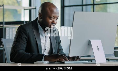 Professional man worker african american 40s businessman millennial ethnic male salesman develop online project work on personal computer in modern Stock Photo