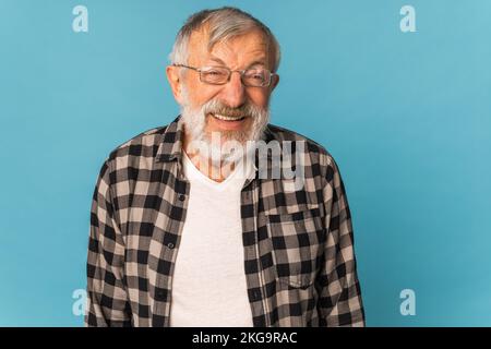 Portrait retired old man with white hair and beard laughter excited over blue color background Stock Photo