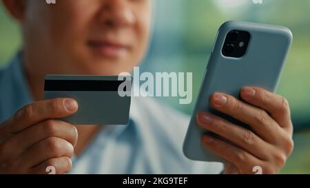 Male customer adult asian man japanese korean buyer businessman paying online in mobile banking app using credit bank card for electronic money Stock Photo