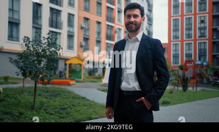 Happy homeowner successful man businessman architect realtor standing in residential city district invest at new modern housing estate with urban Stock Photo