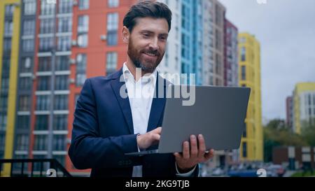 Successful caucasian man adult wealthy businessman professional entrepreneur journalist work freelance outside office in city use portable laptop Stock Photo
