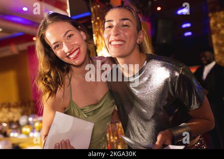 Portrait of two happy caucasian female friends at a nightclub smiling to camera Stock Photo