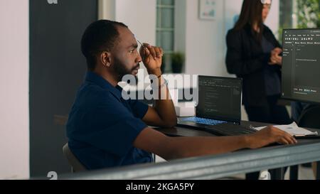 Software developer brainstorming ideas to write code and create new interface in data room. System engineer programming server database in busy artificial intelligence developing agency. Stock Photo