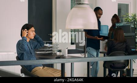 Asian web developer programming firewall server on terminal window, creating new user interface on computer. IT engineer working with coding language and cloud computing in agency office. Stock Photo