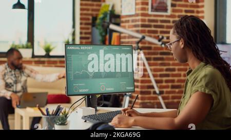 African american woman working remote on data sales report, using financial diagrams on computer. Freelancer doing accounting work on online company network, analyzing internet statistics. Stock Photo