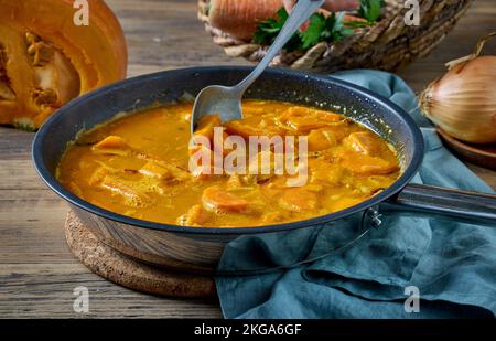 pumpkin and carrot stew in a cooking pan on rustic kitchen table. process of making healthy squash cream soup Stock Photo