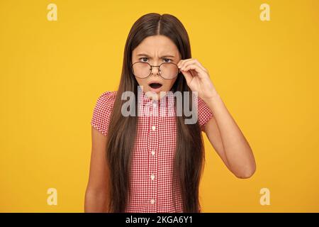 Shocked surprised teenager girl. Ophthalmologist tries on eyeglasses of teenager little girl, close-up. Treatment of childrens vision with glasses. Stock Photo