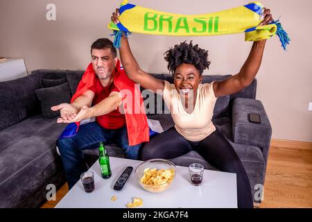 Couple watching a sports event. The husband is cheering for one team, while his wife is for another. Football World cup. Marriage agreements. Stock Photo