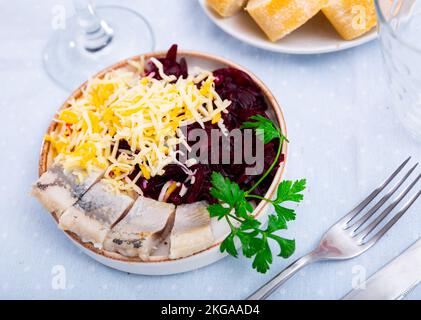 Sliced herring with grated beetroot and cheese served on table Stock Photo