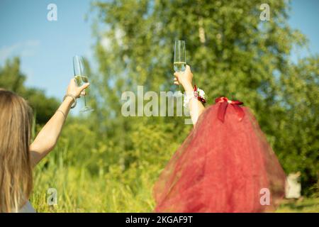 Girls raised glasses of champagne. Alcohol in hand. Drinks at party. Bridesmaids raise toast. Stock Photo
