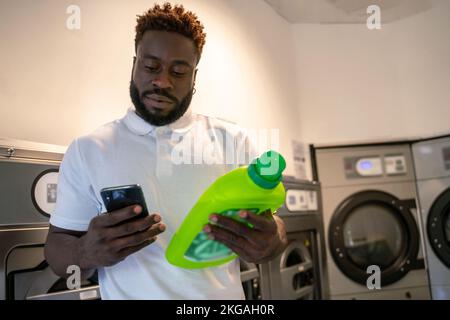 Male using the smartphone at a launderette Stock Photo