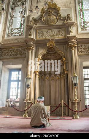 Old man reading Quran in a mosque on display Stock Photo