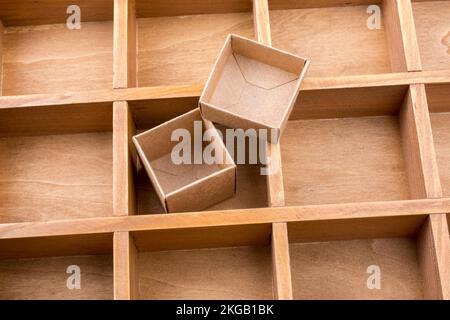 Open cardboard box inside a wooden box with compartments Stock Photo