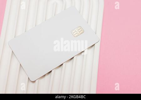 White credit or debit card with chip on the wavy white stone surface, mock-up Stock Photo