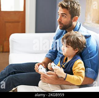 Showing his dad how its done. a father and his young son playing video games. Stock Photo