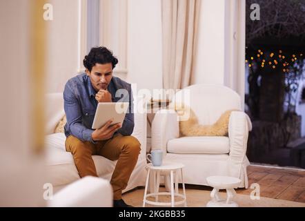 Well this is new. a handsome man using his tablet while relaxing at home. Stock Photo