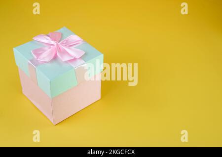 Pink and cyan gift box with ribbon bow isolated on yellow background Stock Photo