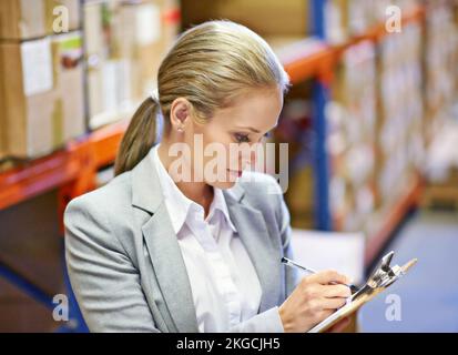 Getting to grips with the numbers. a woman doing an inventory check in a warehouse. Stock Photo