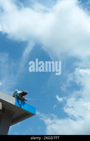 construction workers fixing roof against clouds blue sky, install shingles at the top of the house. Renovate, painting the walls, improvement, build h Stock Photo
