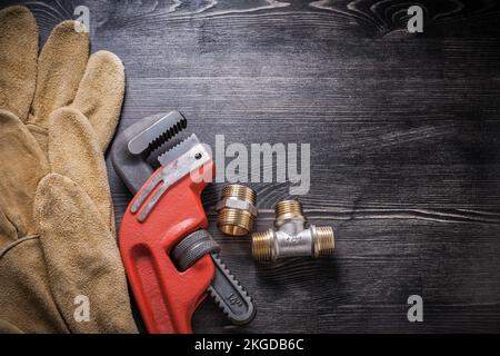 Adjustable wrench plumbing fixtures protective gloves on wooden board. Stock Photo