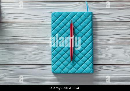 blue classic soft notepad and red ball point pen on vintage painted wood boards Stock Photo