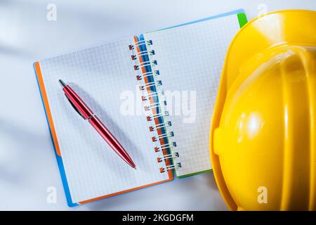Building helmet notepad pen on white background. Stock Photo