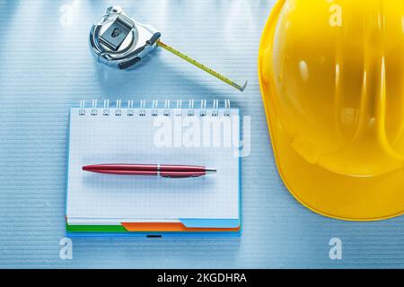 Checked notebook pen hard hat measuring tape. Stock Photo