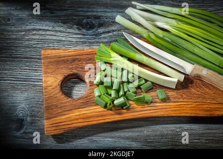 chopped onions and kitchen knife on wooden cutting board vintage wood background Stock Photo