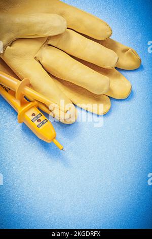 Composition of safety gloves electric tester on blue background electricity concept. Stock Photo