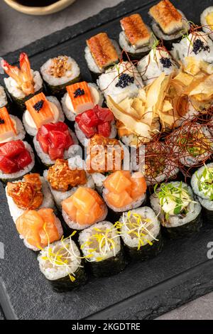 Sushi set of various products on a black stone plate. Blur background and selective focus Stock Photo