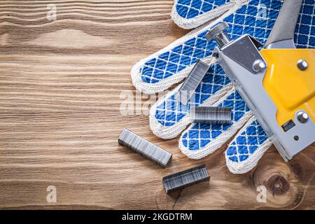 Construction stapler safety gloves staples on wood board. Stock Photo