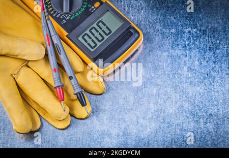 Digital electric tester protective gloves on metallic background. Stock Photo