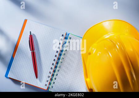 Hard hat checked notepad pen on white background. Stock Photo
