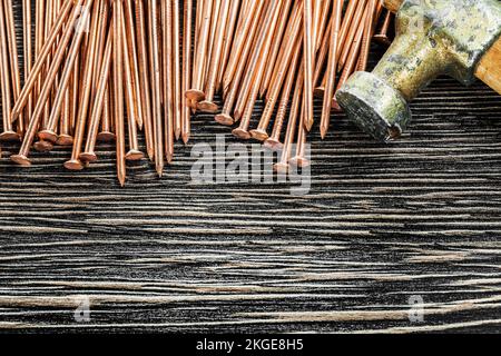 Heap of copper nails claw hammer on wooden board. Stock Photo